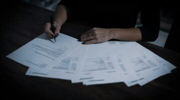 شخص يوقع على مستند ورقي في صورة توضيحية لتقديم الشكوى